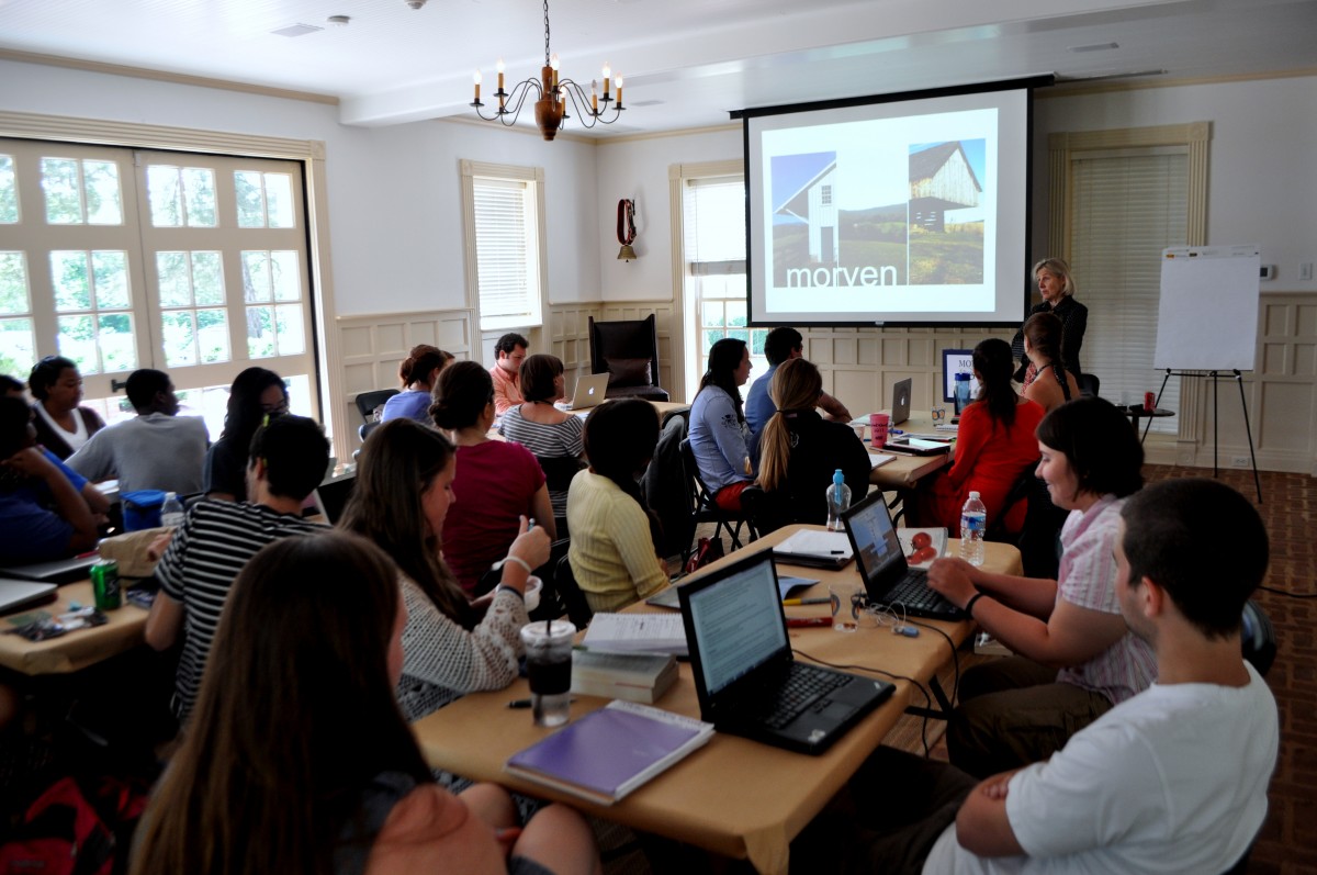 College students sit in dimly lit room looking at projection screen 