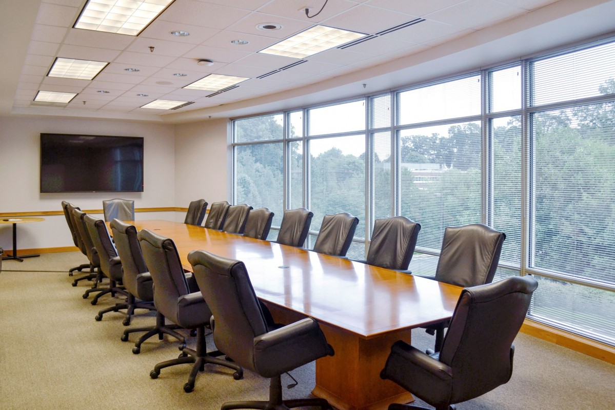 black leather executive chairs surround a long wooden conference table