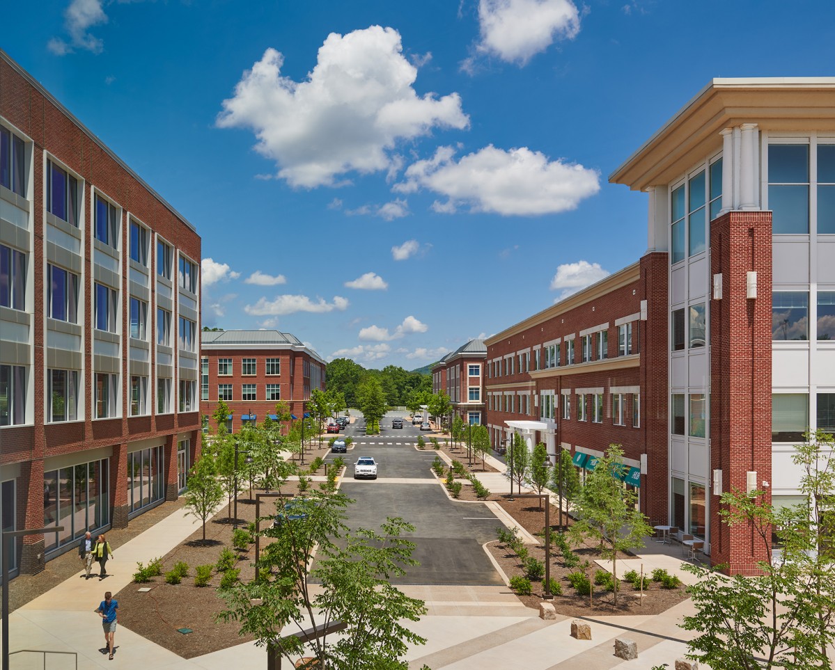 Four brick office buildings flank a boulevard and pedestrian plaza on a bright and sunny day
