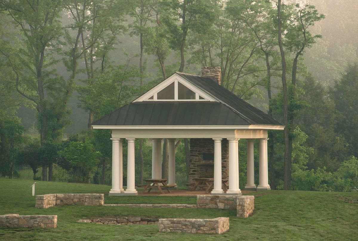 two picnic tables under a picnic pavilion with an old stone fireplace