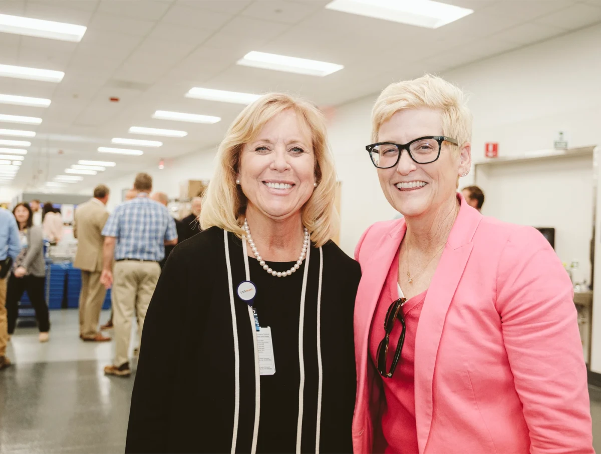 two professional women stand side by side and smile for the camera