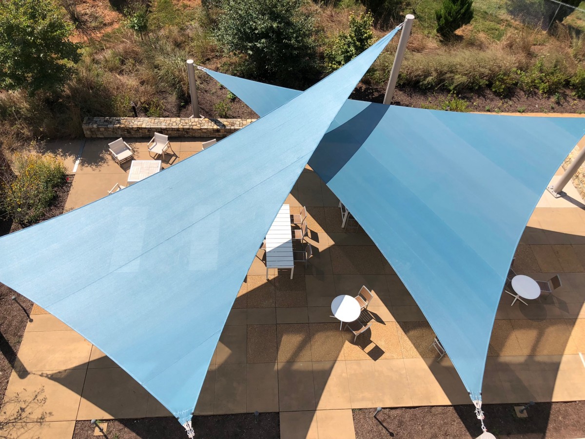 looking down on an outdoor patio shaded by large teal colored sails