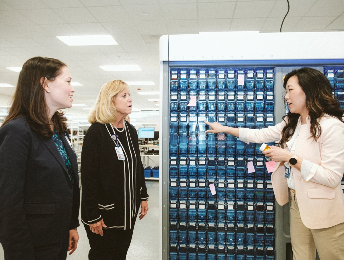 two women look on as a third shows off pharmaceutical equipment
