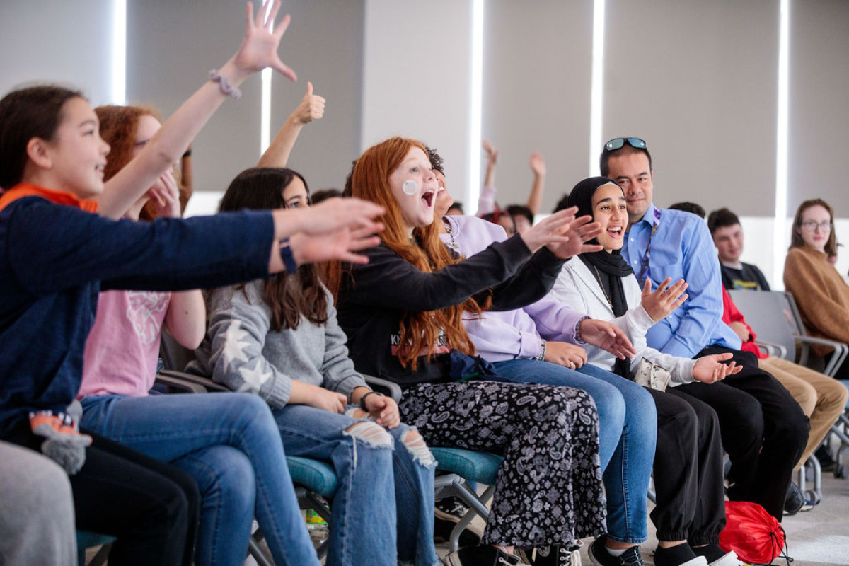 middle school students excitedly raise their hands